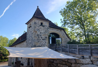 Stenen gebouw met toren en terras in Domaine Papillon vakantiepark in Occitanië, Frankrijk, bij daglicht.