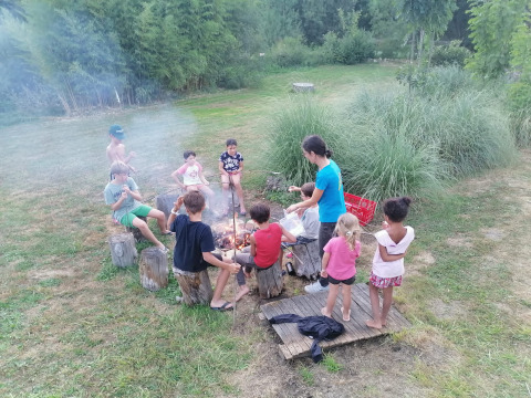 Kinderen en volwassenen rond een kampvuur in Domaine Papillon, een vakantiepark in Occitanië, Frankrijk.