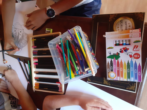 Kinderen tekenen en kleuren met kleurpotloden en stiften aan tafel in Domaine Papillon, Occitanië, Frankrijk.