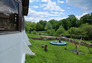 Uitzicht op Domaine Papillon in Occitanië, Frankrijk, met kinderen op trampoline en schommels buiten.