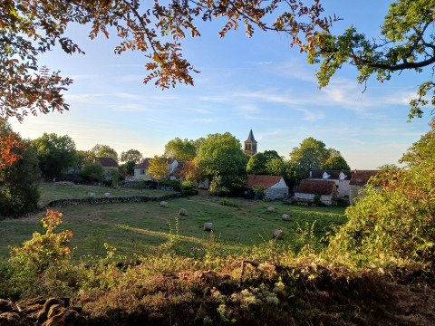 Landschapszicht bij Reyrevignes in Occitanië, Frankrijk, met weilanden, huizen en een kerktoren in de verte.