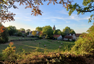 Landschapszicht bij Reyrevignes in Occitanië, Frankrijk, met weilanden, huizen en een kerktoren in de verte.