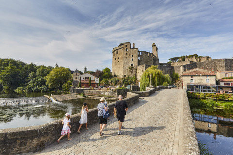Famiglia che passeggia su un ponte di pietra vicino a un castello sul fiume a Saint-Philbert-de-Grand-Lieu, Pays de la Loire.