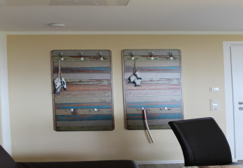 Interior view of lodge Am Strand in Germany featuring colorful wall hooks and black chairs.