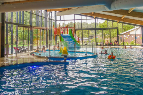 Binnenzwembad met glijbaan bij Velthorst lodge in EuroParcs Ruinen, Nederland, spelende kinderen.