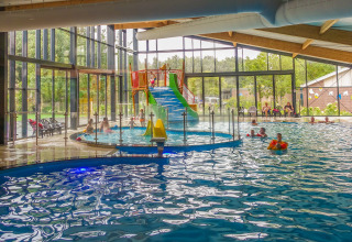 Binnenzwembad met glijbaan bij Velthorst lodge in EuroParcs Ruinen, Nederland, spelende kinderen.