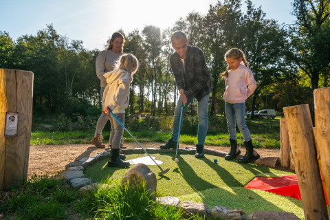Gezin speelt minigolf bij lodge Velthorst in EuroParcs Ruinen, Nederland, op een zonnige dag buiten.