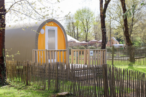 Tenda safari Coco Sweet in un campeggio soleggiato, circondata da una recinzione in legno e alberi verdi.