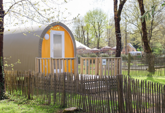 Tenda safari Coco Sweet in un campeggio soleggiato, circondata da una recinzione in legno e alberi verdi.