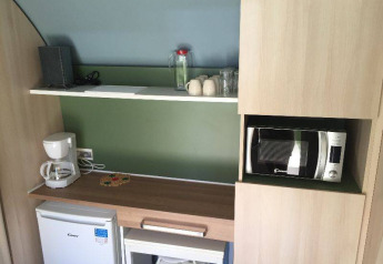 Un piccolo angolo cottura in una tenda safari Coco Sweet al Camping les Rives de Grand Lieu in Francia, con macchina da caffè, microonde e mini frigo.