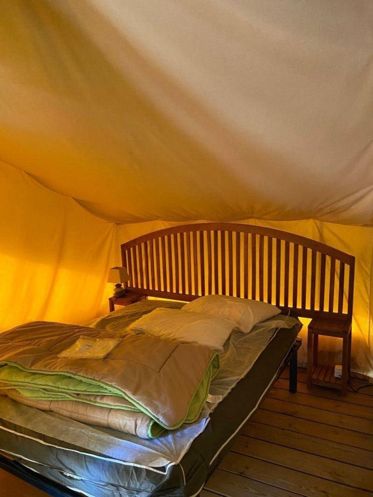 Sfeervol interieur van de Lodge Balearic safaritent bij Camping les Rives de Grand Lieu, met bed en houten meubels.