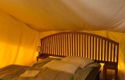 Interno della tenda safari Lodge Balearic al Camping les Rives de Grand Lieu, Francia, con letto e arredi in legno.