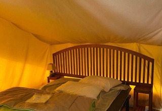 Interno della tenda safari Lodge Balearic al Camping les Rives de Grand Lieu, Francia, con letto e arredi in legno.