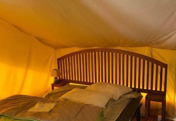 Interno della tenda safari Lodge Balearic al Camping les Rives de Grand Lieu, Francia, con letto e arredi in legno.