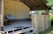 Tenda safari Kenya Lodge al Camping les Rives de Grand Lieu in Francia con terrazza in legno e sedute.