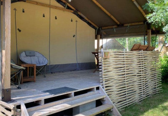 Tenda safari Kenya Lodge al Camping les Rives de Grand Lieu in Francia con terrazza in legno e sedute.
