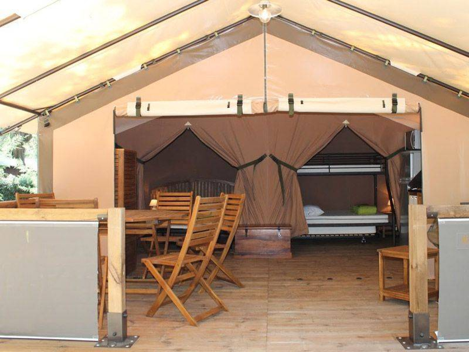 Binnenaanzicht van de Kenya Lodge safaritent bij Camping les Rives de Grand Lieu in Frankrijk, met houten meubels.
