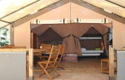 Vista interna della tenda safari Kenya Lodge al Camping les Rives de Grand Lieu in Francia, con arredi in legno.