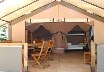 Vista interna della tenda safari Kenya Lodge al Camping les Rives de Grand Lieu in Francia, con arredi in legno.