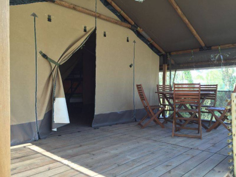 Tenda safari Kenya Lodge al Camping les Rives de Grand Lieu in Francia con veranda in legno e sedie.