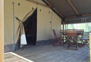 Tenda safari Kenya Lodge al Camping les Rives de Grand Lieu in Francia con veranda in legno e sedie.