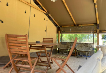 Tenda safari Kenya Lodge al Camping les Rives de Grand Lieu in Francia con mobili e sedie in legno.