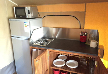 Angolo cucina nella tenda safari Kenya Lodge con fornello, frigo, microonde e stoviglie, Francia.