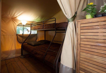 Interno di una tenda safari al Kenya Lodge con letto a castello, pavimento in legno e piante in Francia.