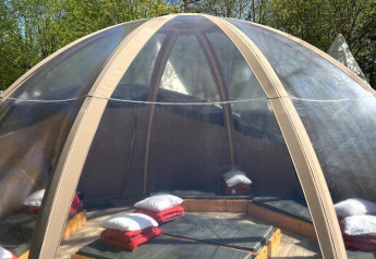 Casa natura Transparent Bell al Camping les Rives de Grand Lieu, con cuscini all’interno di una cupola trasparente.
