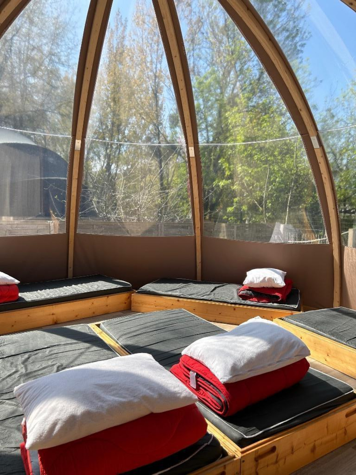 Interieur van het Transparent Bell natuurhuis op Camping les Rives de Grand Lieu in Frankrijk met bedden.