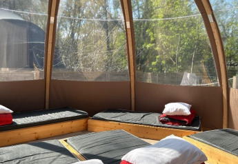 Interno della Transparent Bell al Camping les Rives de Grand Lieu, Francia, con letti e cuscini esposti.