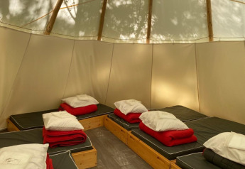 Interno delle Tipi Tents al Camping les Rives de Grand Lieu in Francia, con diversi letti e biancheria rossa.