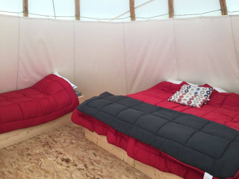 Interno di una tenda Tipi con due letti e biancheria rossa al Camping les Rives de Grand Lieu in Francia.