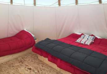 Interno di una tenda Tipi con due letti e biancheria rossa al Camping les Rives de Grand Lieu in Francia.
