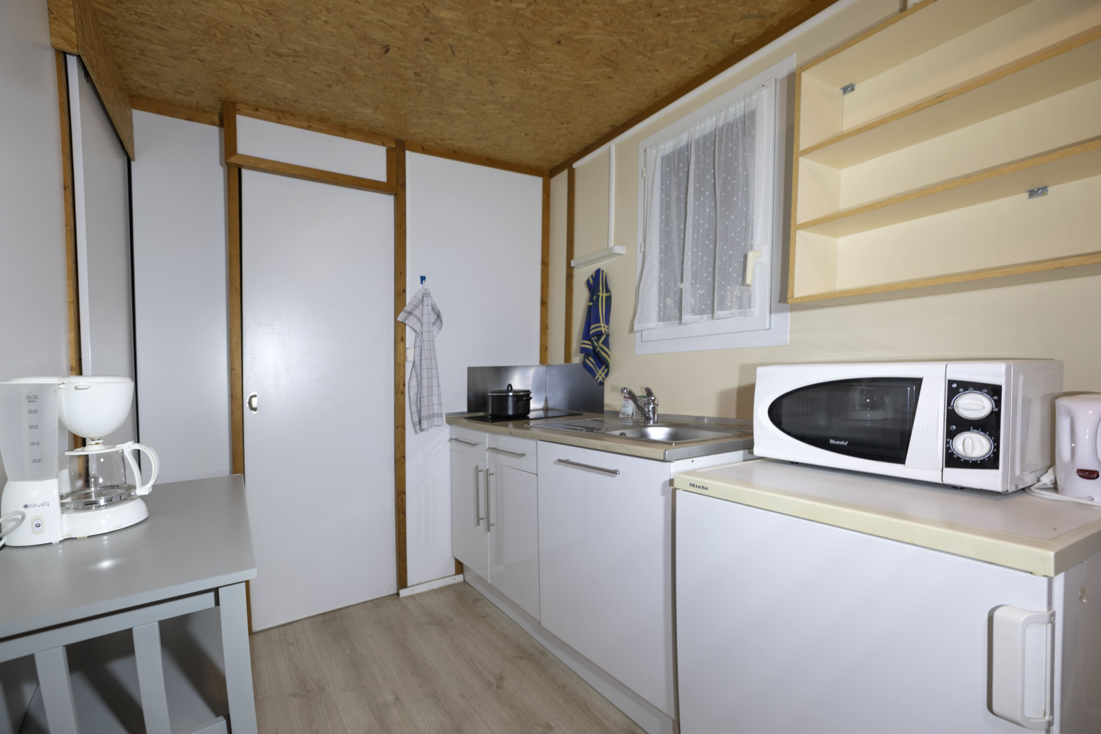 Lichte kitchenette in Cottage Aporia bij Domaine Papillon, Frankrijk, met magnetron, koelkast en koffiezetapparaat.
