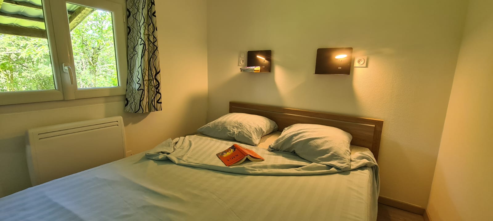 Knusse slaapkamer met tweepersoonsbed, kussens en raam in Chalet Etoilé, Domaine Papillon in Frankrijk.