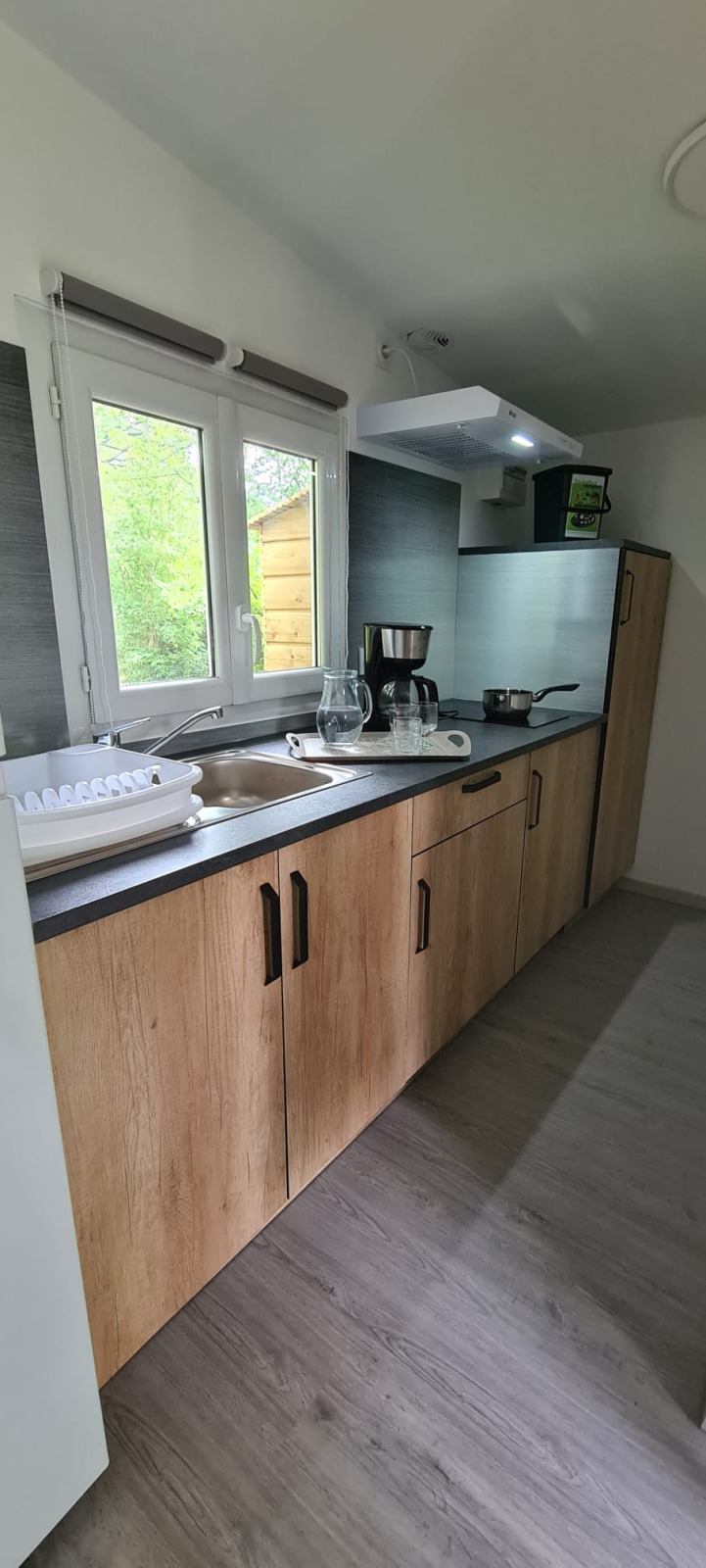 Moderne kitchenette met houten kasten, gootsteen en raam in Chalet Etoilé, Domaine Papillon, Frankrijk.