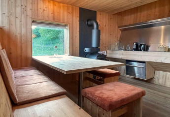 Modernes, holzgetäfeltes Küchen- und Esszimmer im Ufogel Naturhaus in Österreich mit großem Fenster.