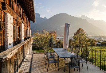 Terrasse des Naturhauses Ufogel in Österreich mit Sitzgruppe und Blick auf Berge im Sonnenlicht.
