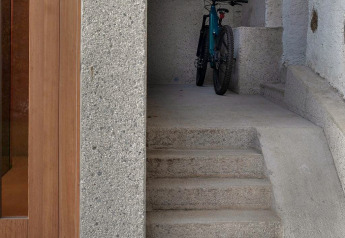 Betontreppe und Rampe neben Holztür, oben ein Fahrrad, Ufogel Naturhaus in Österreich.