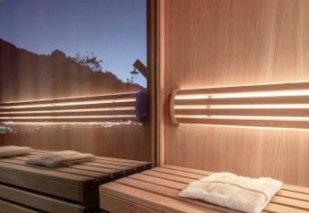 Innenaufnahme einer Sauna im Ufogel-Naturhaus in Österreich mit Holzbänken und Bergblick bei Sonnenuntergang.
