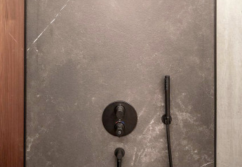 Moderne schwarze Dusche in einem stilvollen Badezimmer im Ufogel Naturhaus, Österreich, mit dunklen Wänden.