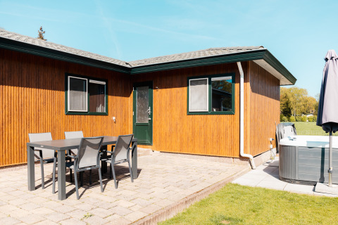 Outdoor patio at Wilbrinkchalet, Recreation park De Boshoek, Netherlands, featuring dining table, chairs, and hot tub.