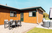 Udendørs terrasse ved Wilbrinkchalet på De Boshoek, Holland, med spisebord, stole og jacuzzi på flisebelagt område.