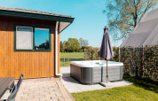 Espace extérieur du Wilbrinkchalet avec jacuzzi, parasol et vue sur les champs à De Boshoek, Pays-Bas.