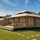 Safari tent Stardust 40 Family Lodge met houten terras en tuinmeubelen in een groene omgeving.