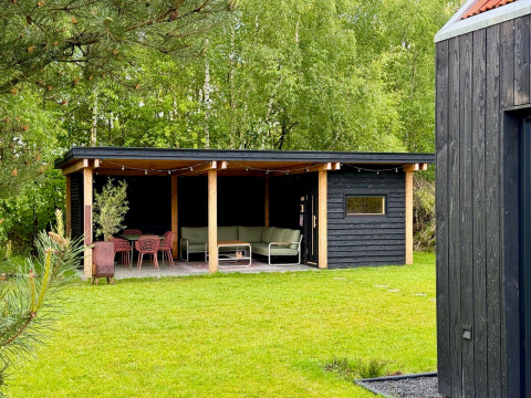 Veranda coperta alla Forest villa «De Bosburcht» a De Kremmer con sedute moderne immersa nel verde.