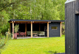 Overdekt terras bij Forest villa «De Bosburcht» in De Kremmer, omringd door groen, bomen en moderne meubels.