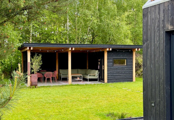 Overdekt terras bij Forest villa «De Bosburcht» in De Kremmer, omringd door groen, bomen en moderne meubels.