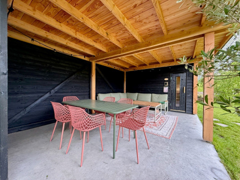 Terrazza coperta con soffitto in legno, tavolo verde e sedie rosa alla Forest villa De Bosburcht, Paesi Bassi.